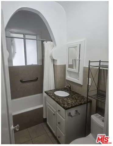 a bathroom with a granite countertop sink a toilet and bathtub