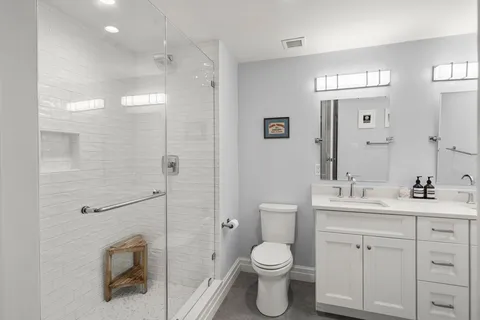 a bathroom with a toilet a sink a glass door a shower and mirror