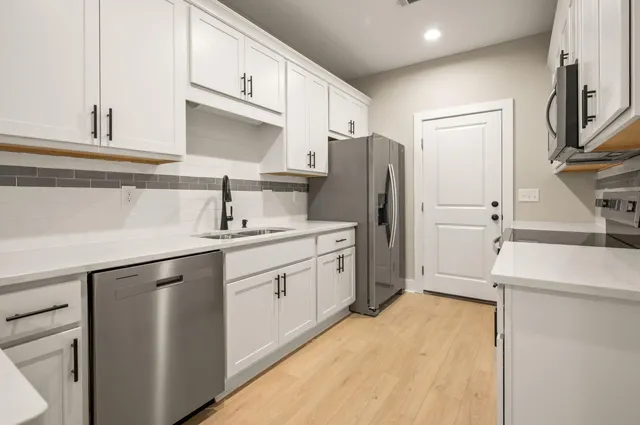 a kitchen with a sink a refrigerator and cabinets