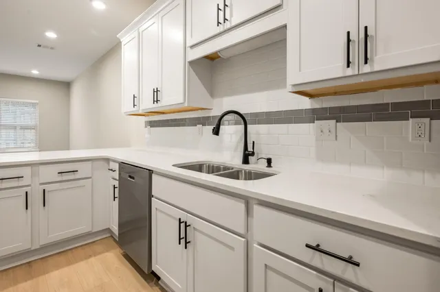 a kitchen with white cabinets appliances and a sink