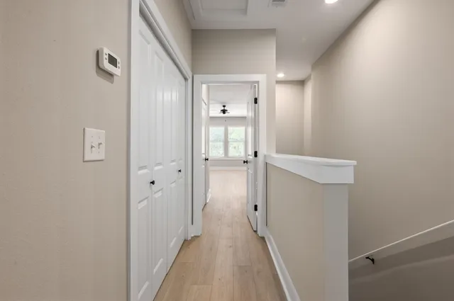 a view of a hallway with closet and wooden floor