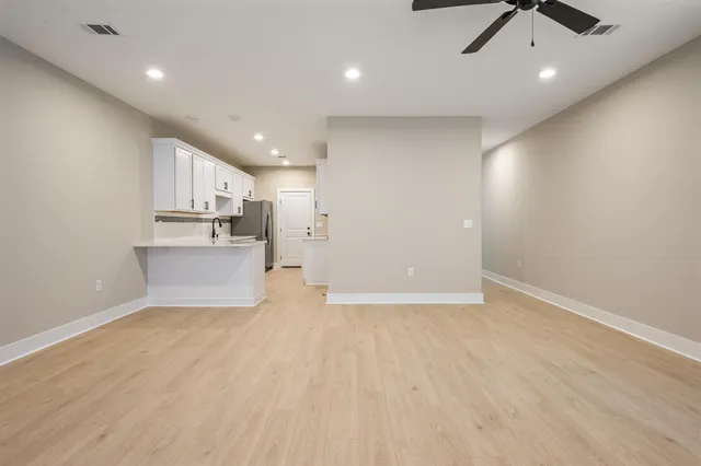 a view of kitchen and empty room with wooden floor