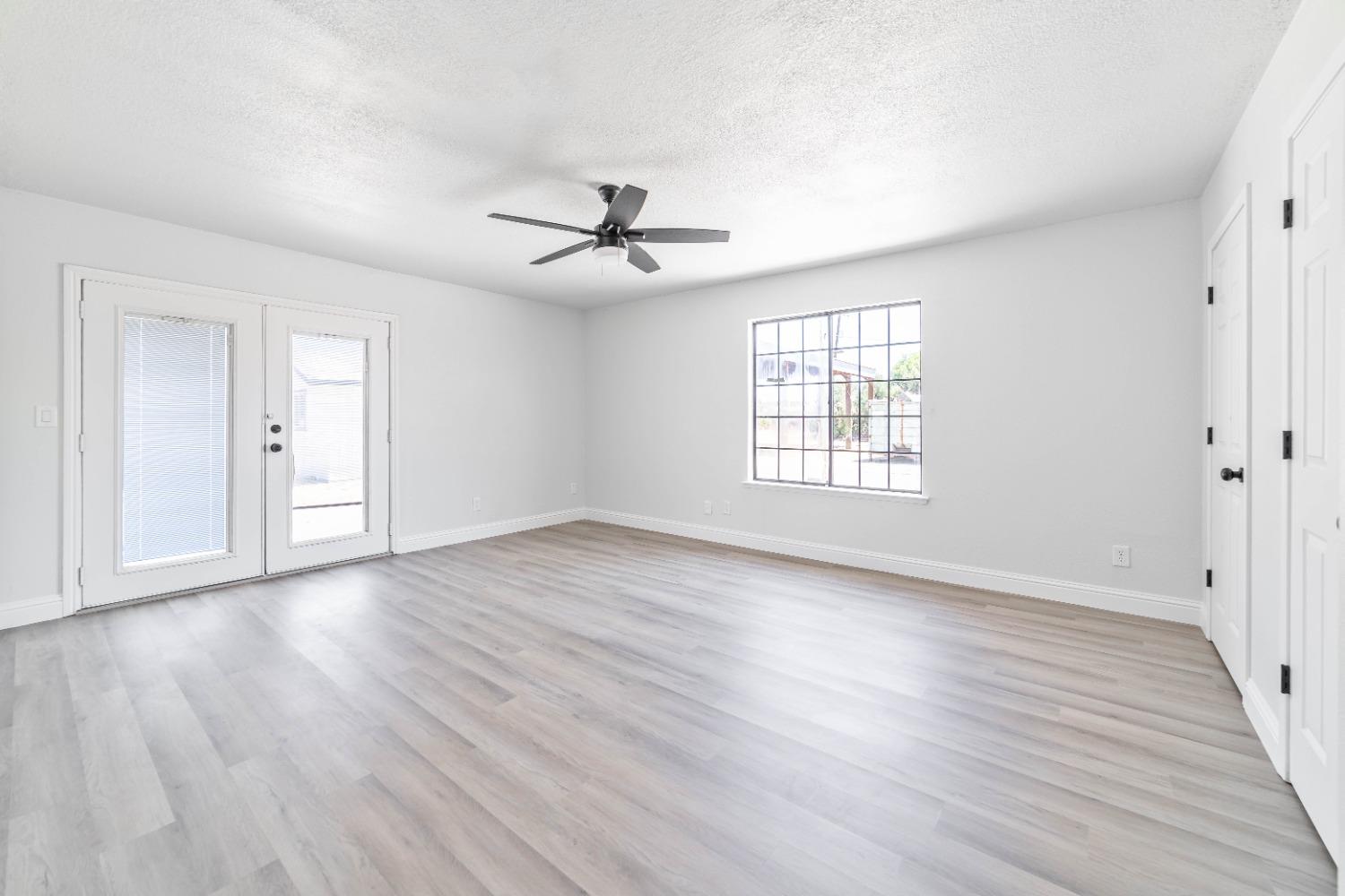 16680 Austin Street Madera, CA 93638 - Photo 12 of 40 an empty room with wooden floor ceiling fan and windows