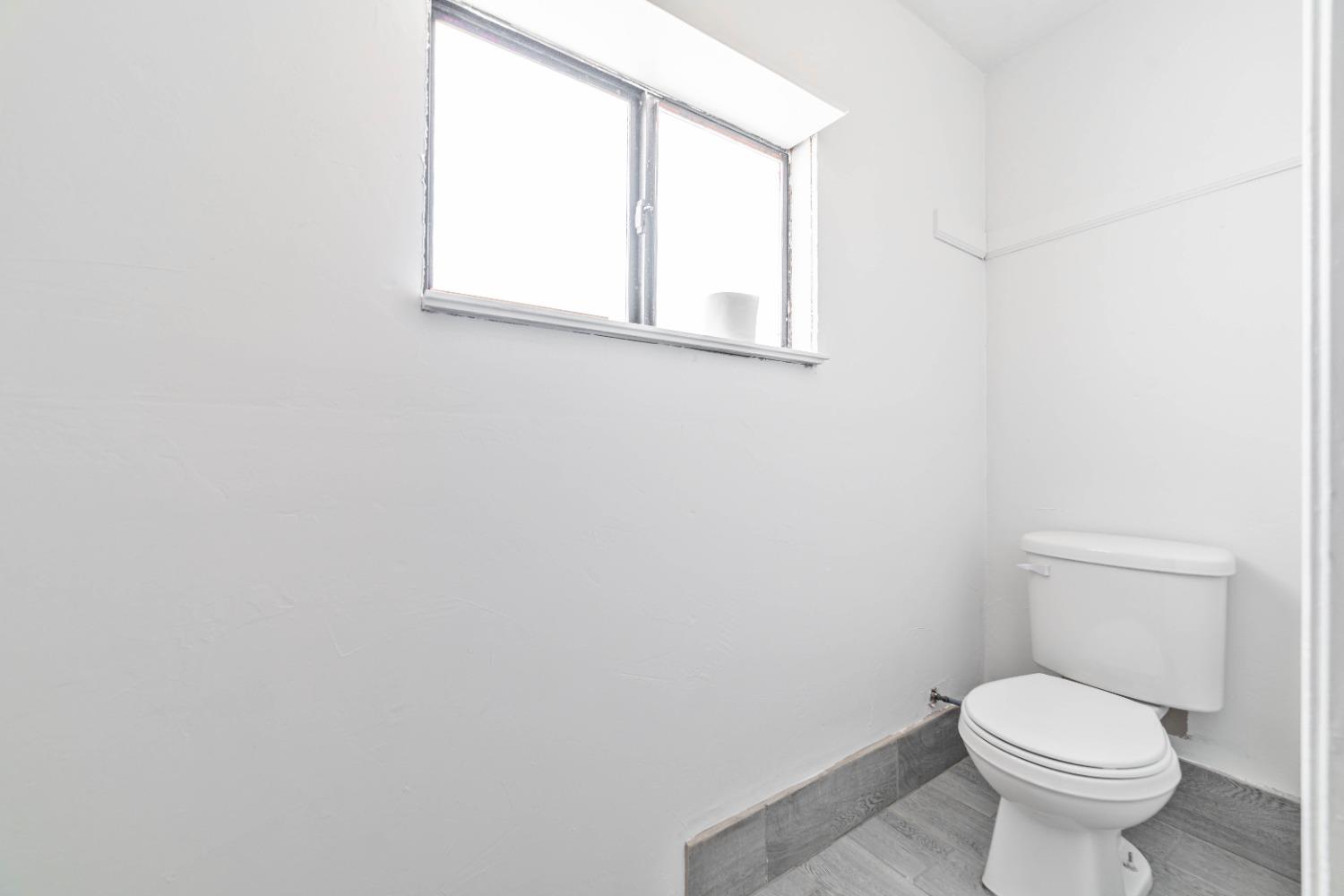 16680 Austin Street Madera, CA 93638 - Photo 37 of 40 a white toilet sitting next to a white sink and a window