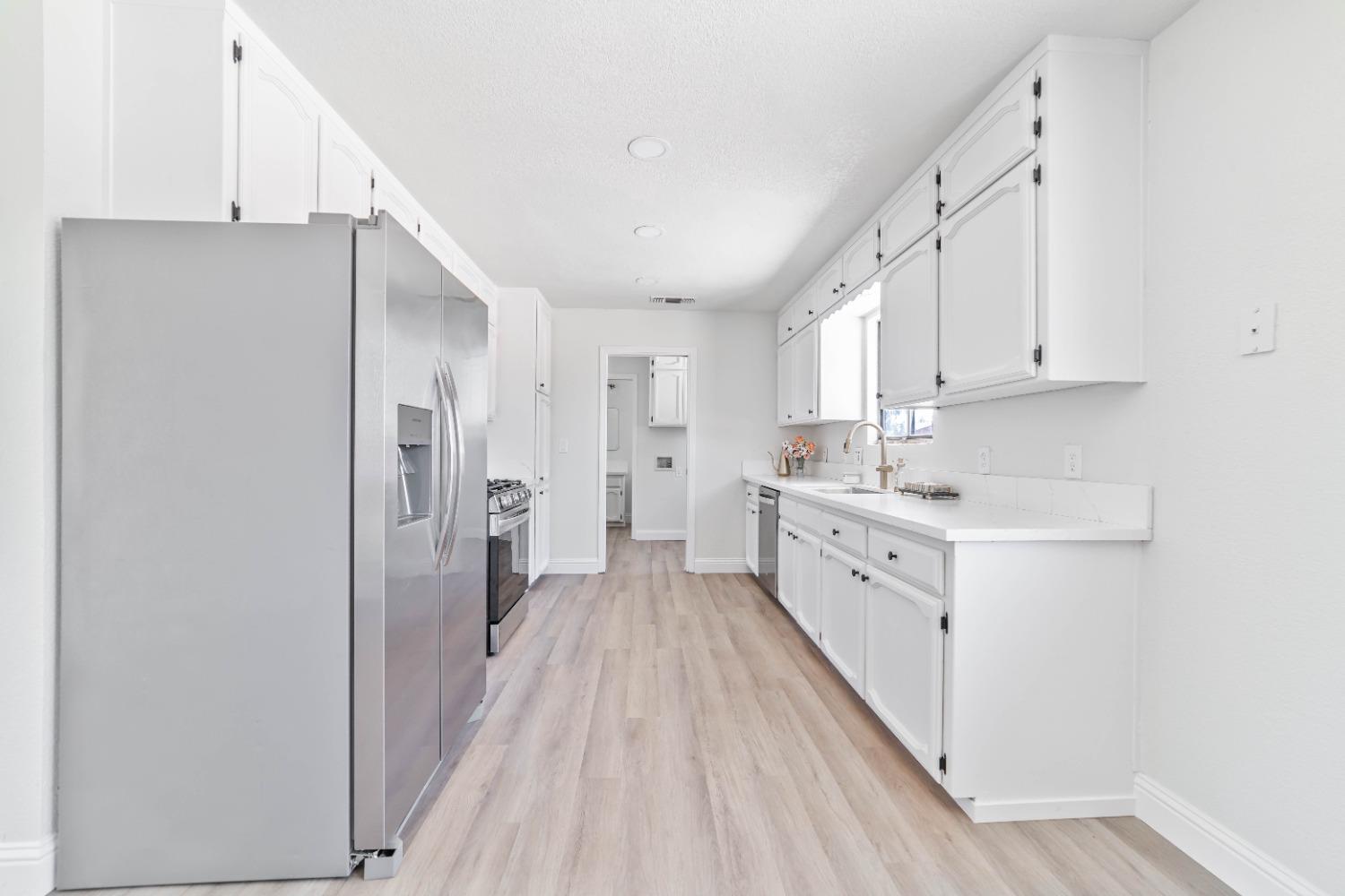 16680 Austin Street Madera, CA 93638 - Photo 4 of 40 a kitchen with white cabinets and white appliances
