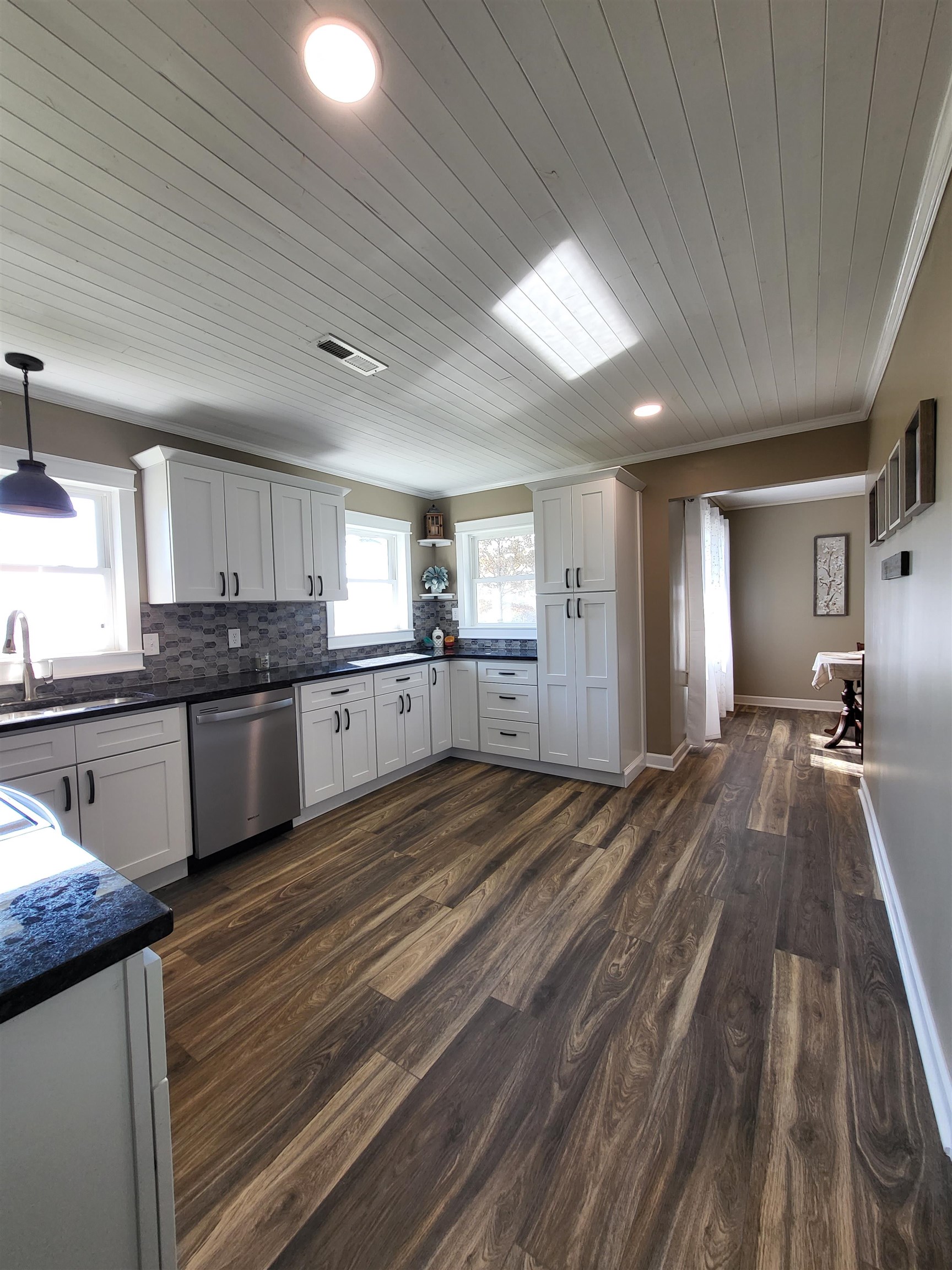 3637 Lightfoot Luckett Road Ripley, TN 38063 - Photo 12 of 25 a large kitchen with kitchen island a stove a sink dishwasher a refrigerator and white cabinets with wooden floor