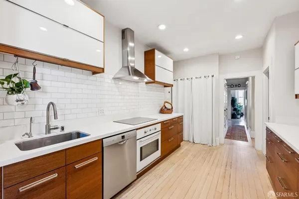 a kitchen with stainless steel appliances a sink dishwasher a refrigerator and a stove with wooden floor