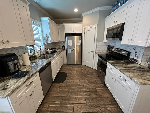 a kitchen with stainless steel appliances granite countertop a stove top oven a sink dishwasher a refrigerator and a oven with wooden floor