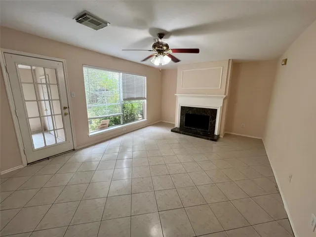 a living room with a fireplace furniture a ceiling fan and a window
