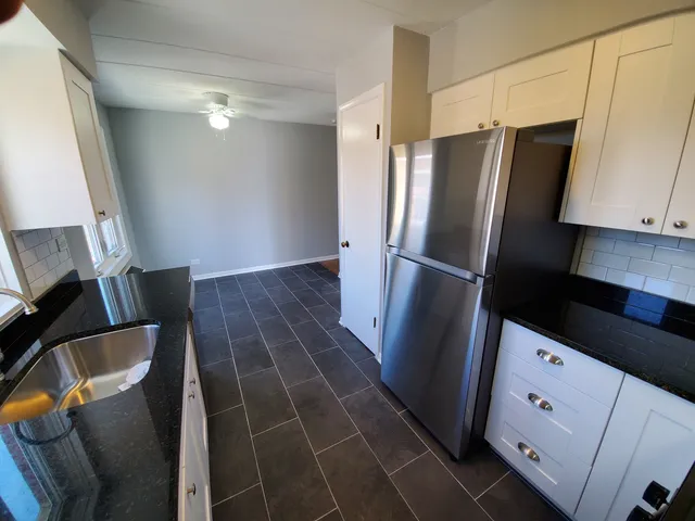 a view of a kitchen with refrigerator and wooden floor