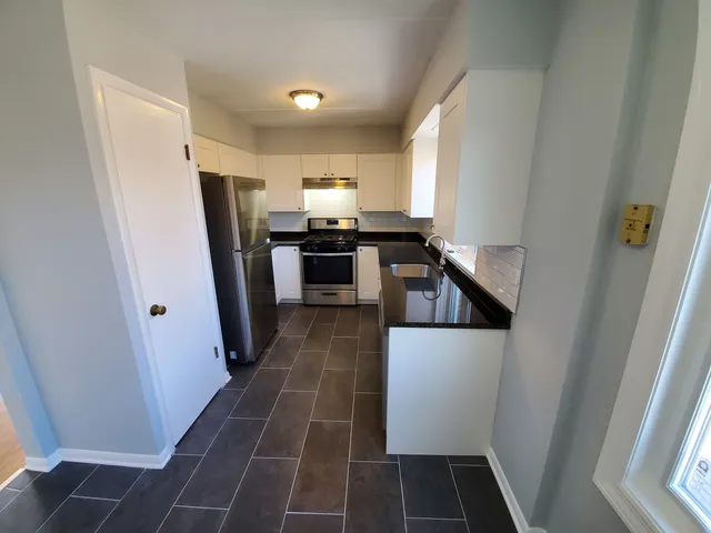 a kitchen with a refrigerator a stove top oven and cabinets