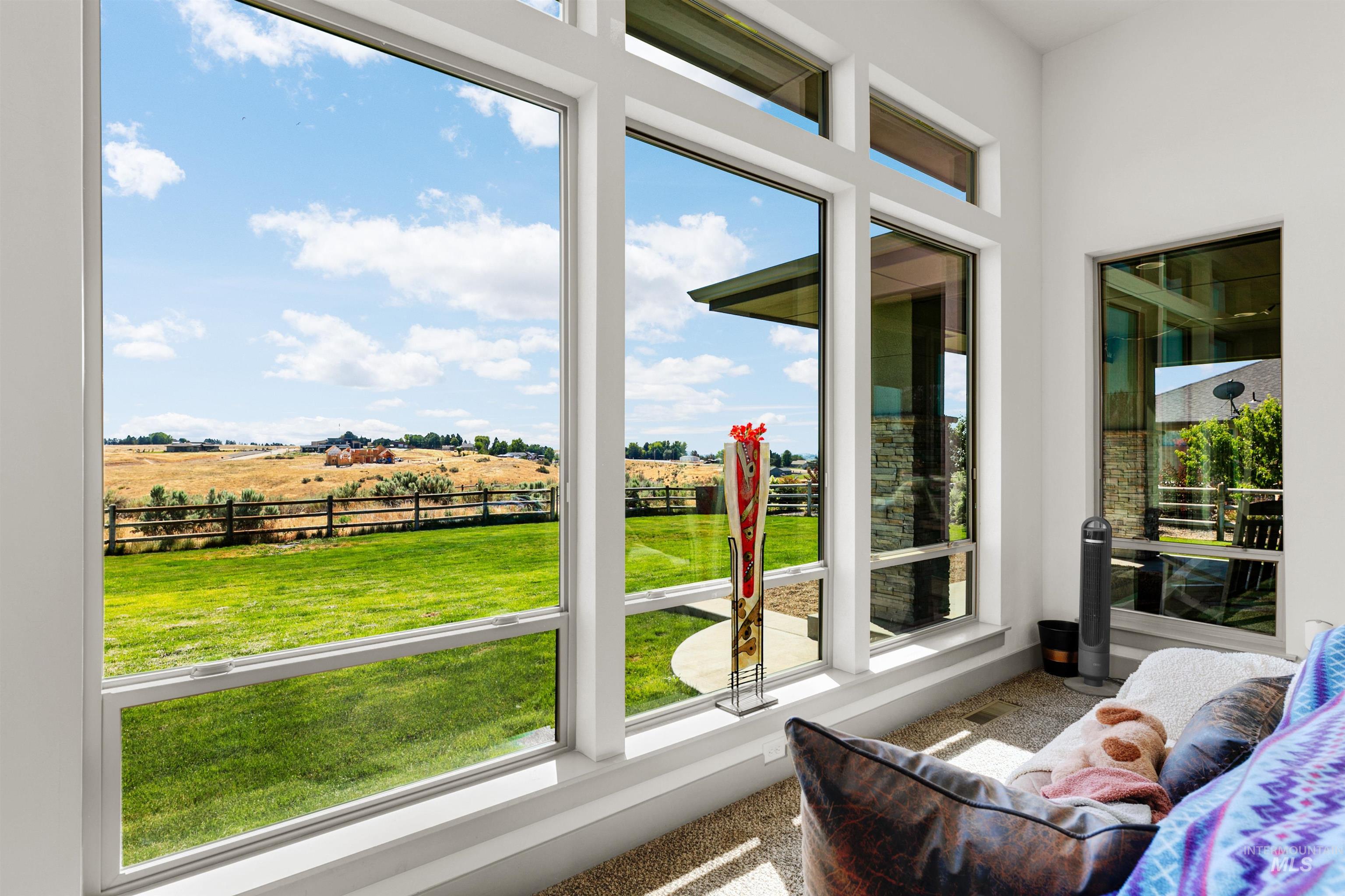 24398 Tombstone Ridge Court Middleton, ID 83644 - Photo 27 of 47 Expansive window walls frame the outdoor environment, showcasing a green lawn and distant rolling hills