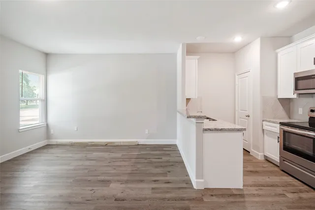 a view of a kitchen with wooden floor electronic appliances and windows
