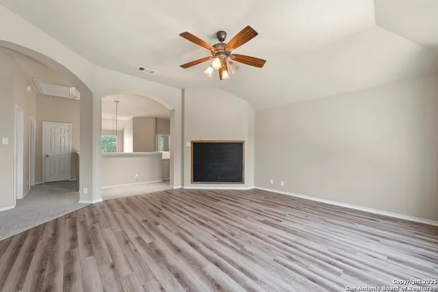 a view of an empty room with window and wooden floor