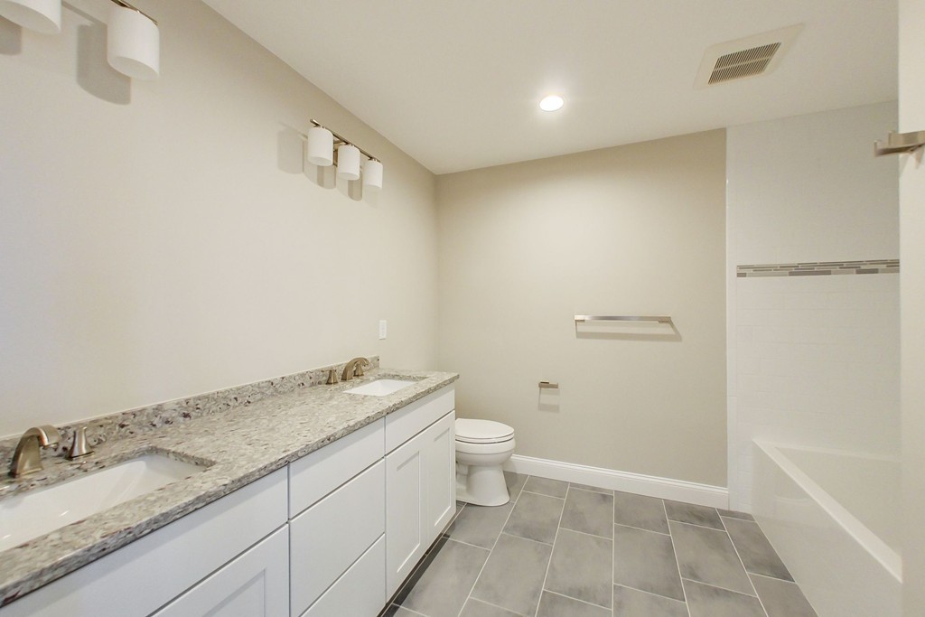 38 Cherry Street, Unit B Hudson, MA 01749 - Photo 16 of 38 a bathroom with a granite countertop sink a toilet and shower