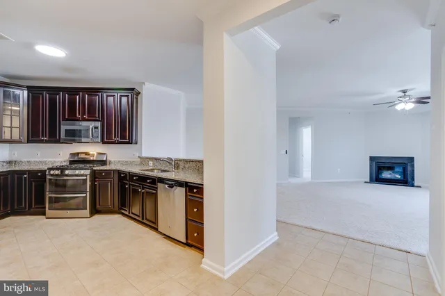 a kitchen with granite countertop stainless steel appliances wooden cabinets a stove a sink and a window