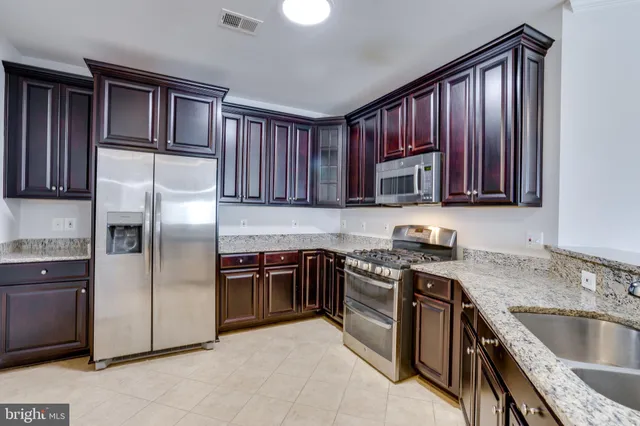 a kitchen with granite countertop a stove top oven microwave and cabinets