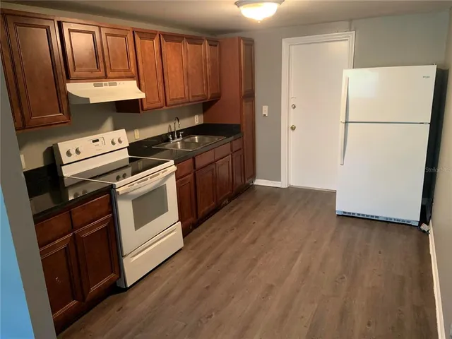 a kitchen with a refrigerator stove and wooden cabinets