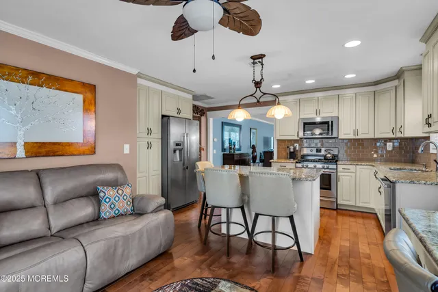 a living room with stainless steel appliances kitchen island granite countertop furniture and a wooden floor