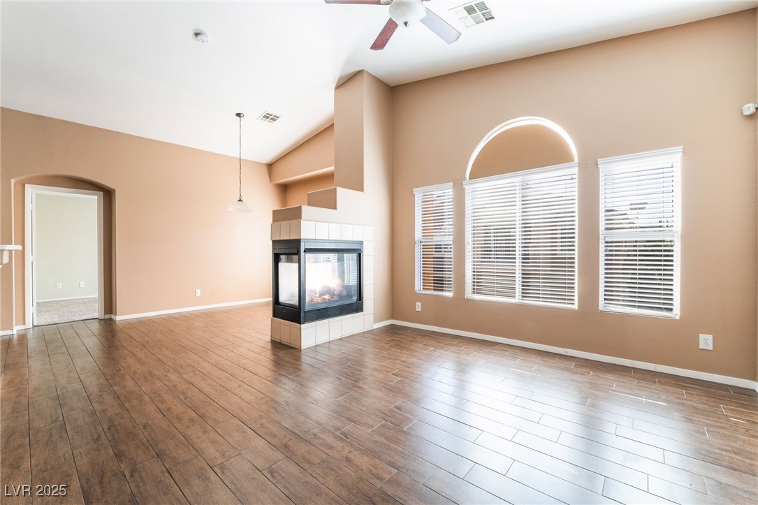 1570 Rusty Ridge Lane Henderson, NV 89002 - Photo 12 of 35 Unfurnished living room featuring a multi sided fireplace, wood finished floors, a ceiling fan, and visible vents
