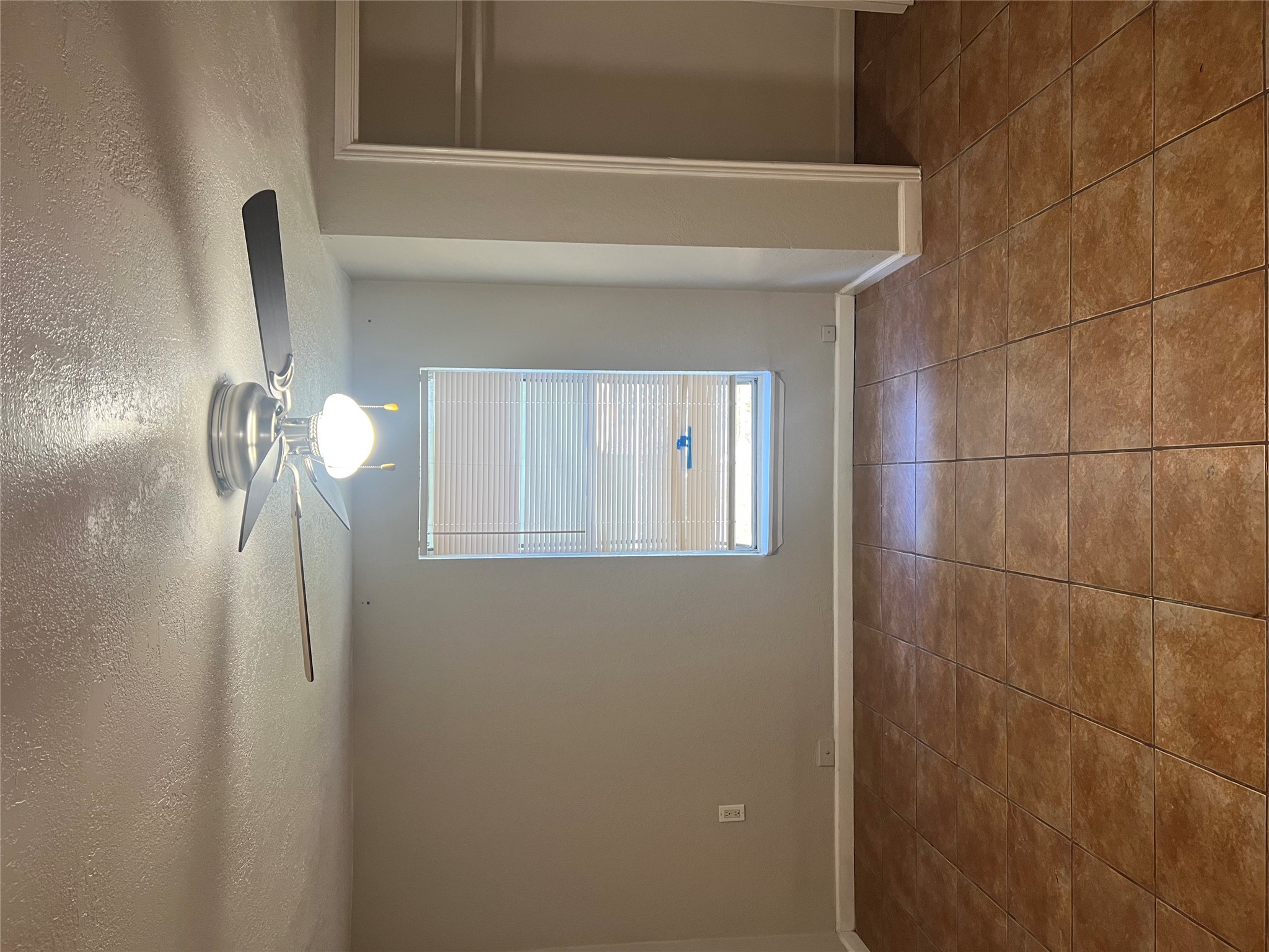 6405 Torres Street Austin, TX 78741 - Photo 5 of 14 Well-appointed bedroom with a ceiling fan, window, and durable tile flooring.