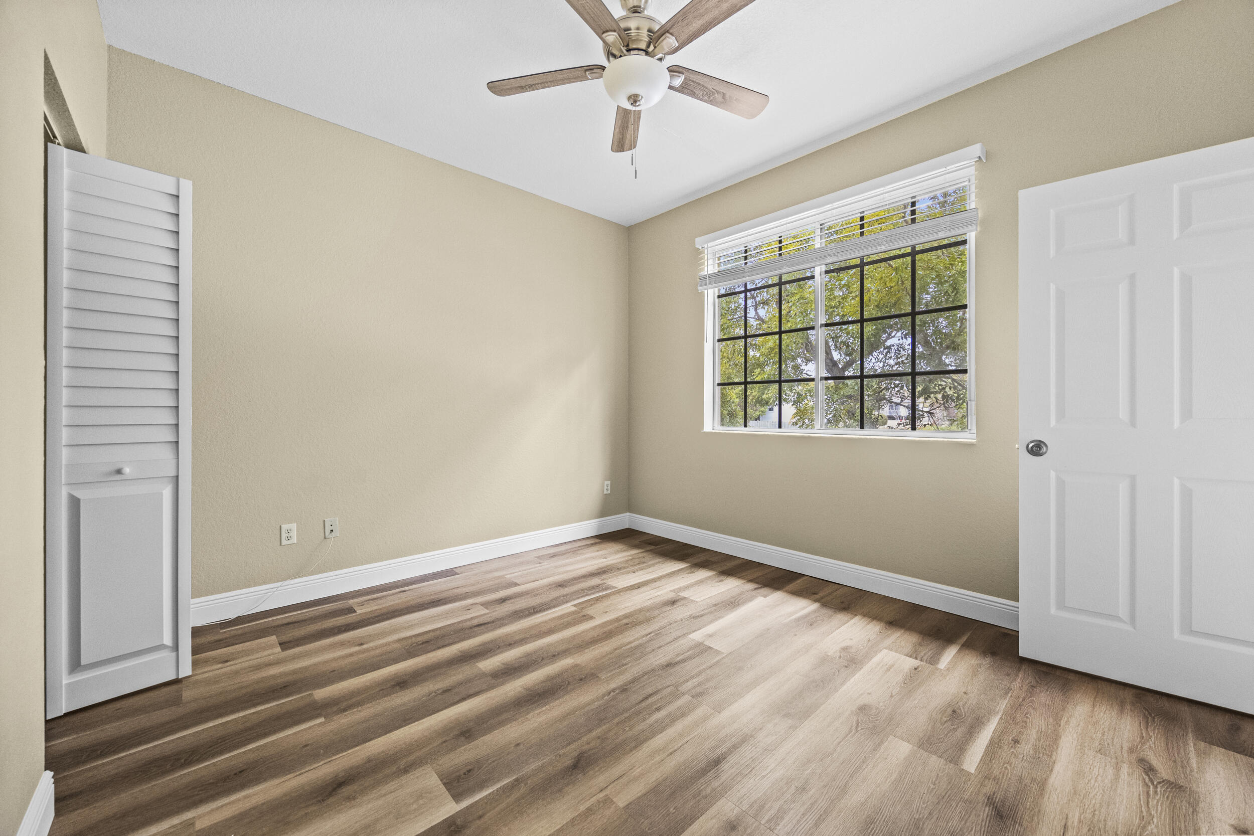 1982 Freeport Drive Riviera Beach, FL 33404 - Photo 21 of 29 an empty room with wooden floor chandelier fan and windows