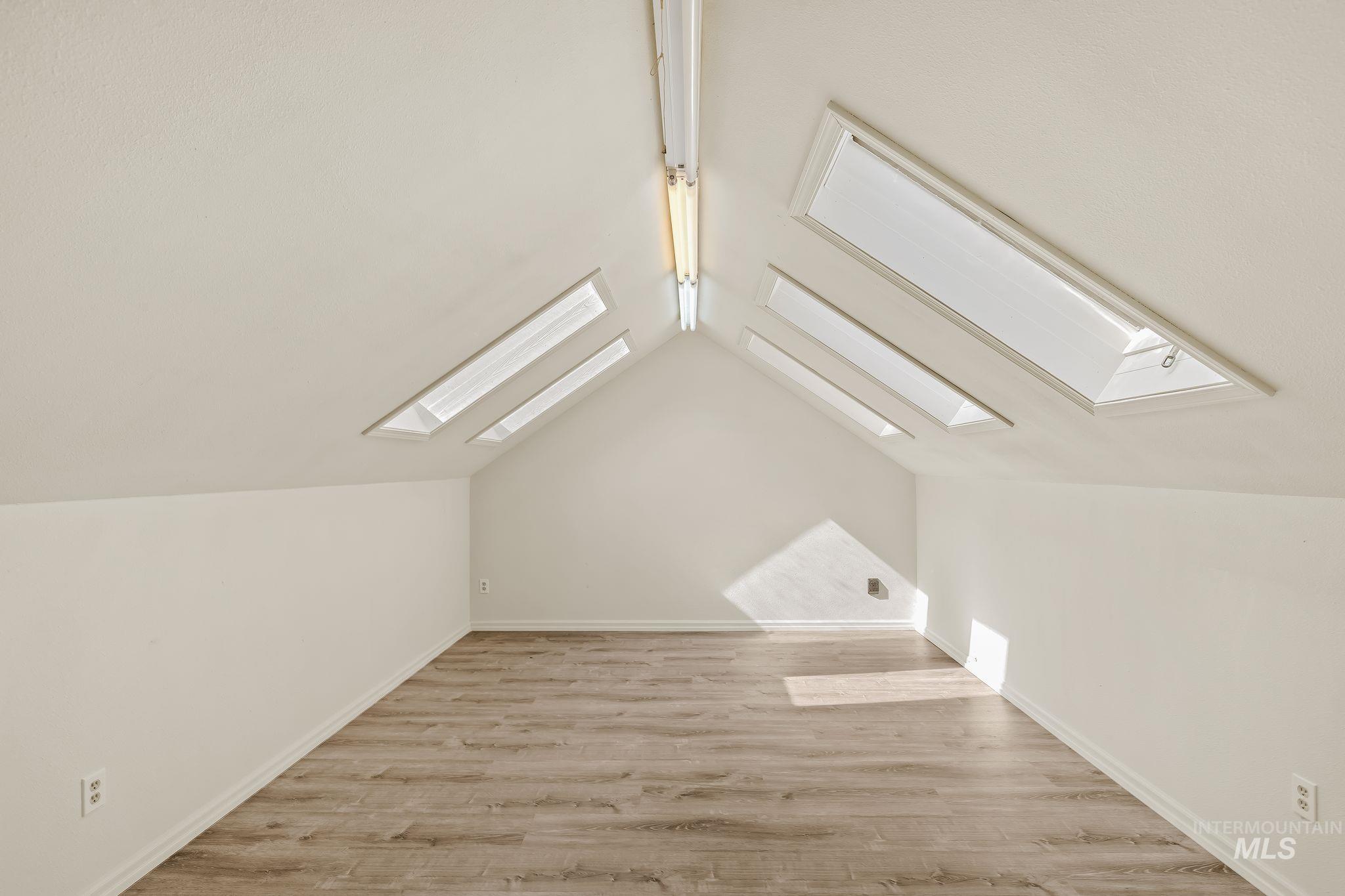531 Silcott Road Clarkston, WA 99403 - Photo 25 of 43 Vaulted ceiling with multiple skylights, wood-finish flooring, and track lighting