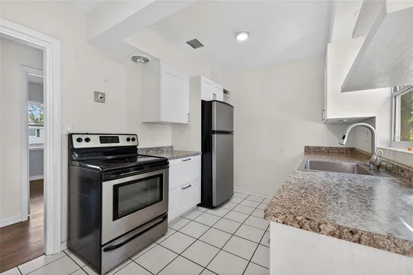 a kitchen with granite countertop a sink stove and refrigerator