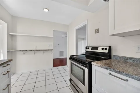 a kitchen with granite countertop a stove a sink and a refrigerator