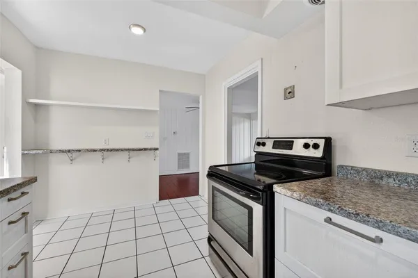 a kitchen with granite countertop a stove a sink and a refrigerator
