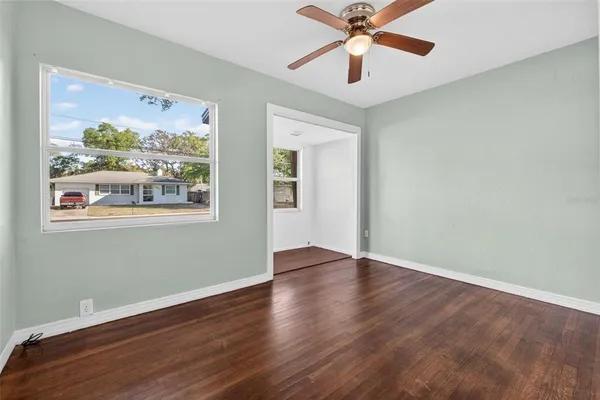 a view of an empty room with wooden floor and a window