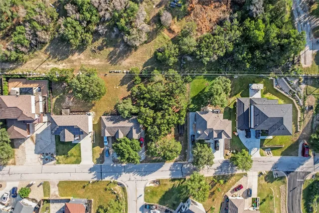 an aerial view of residential houses with outdoor space and trees