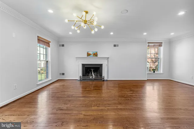 an empty room with windows fireplace and wooden floor