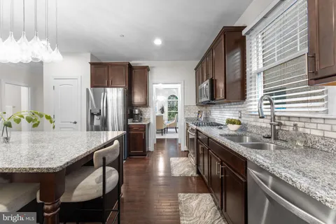 a kitchen with stainless steel appliances granite countertop a kitchen island hardwood floor sink stove and refrigerator