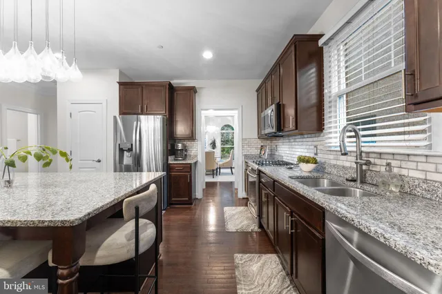 a kitchen with stainless steel appliances granite countertop a kitchen island hardwood floor sink stove and refrigerator