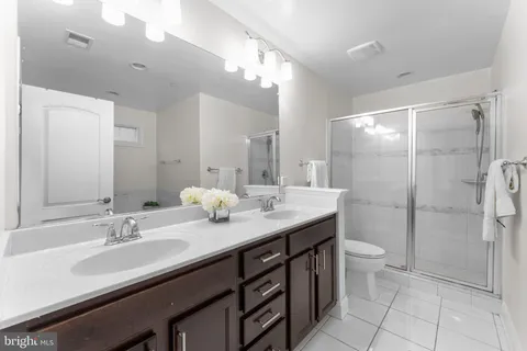 a bathroom with a granite countertop sink a toilet a mirror and shower