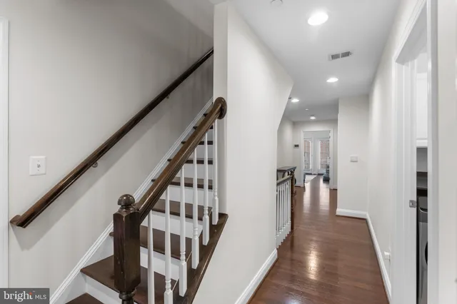 a view of a hallway with wooden floor and staircase