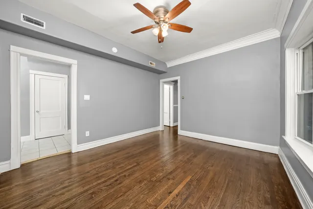a view of an empty room with window and wooden floor