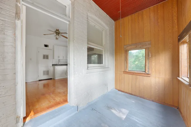a view of a hallway with wooden floor and a bathroom