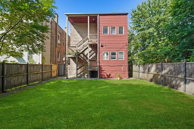 a view of a backyard with plants and a large tree