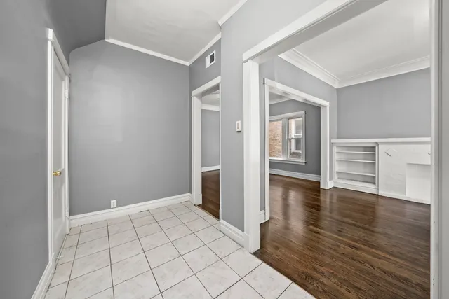 a view of an empty room with window and wooden floor