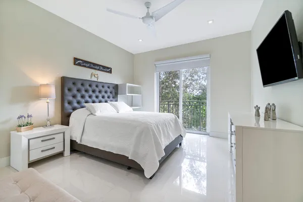 a bedroom with a bed and a flat tv screen on dresser