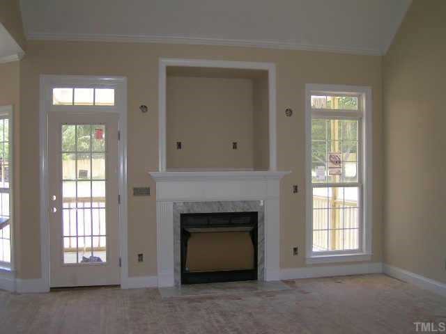 2438 Rolling Tracks Road Willow Spring, NC 27592 - Photo 3 of 8 an empty room with windows and fireplace