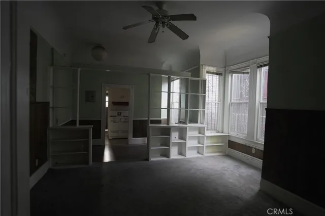 an empty room with windows and ceiling fan