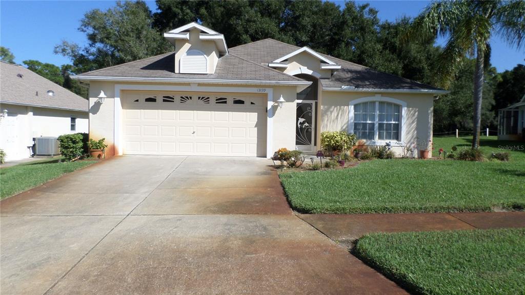 13139 Golf Ridge Place Hudson, FL 34669 - Photo 1 of 1 a front view of a house with a garden and plants