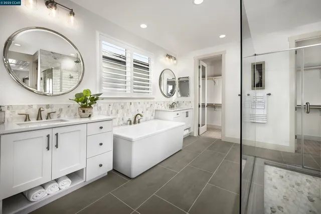 a spacious bathroom with a double vanity sink mirror and bathtub