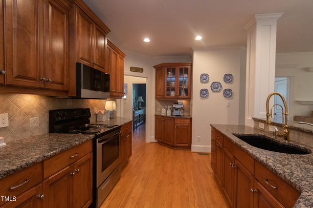 a kitchen with stainless steel appliances kitchen island granite countertop a refrigerator a stove a microwave oven with white cabinets and wooden floor