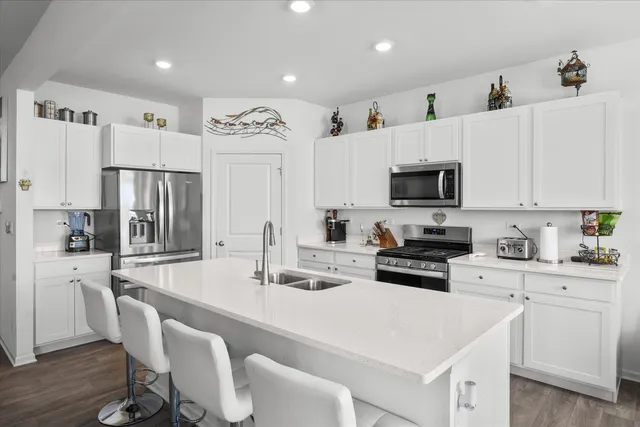 a kitchen with stainless steel appliances a stove a sink a microwave a refrigerator and cabinets