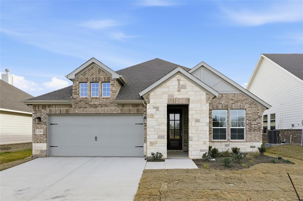 1244 Sabine River Lane Springtown, TX 76082 - Photo 2 of 26 View of front facade with roof with shingles, stone siding, concrete driveway, brick siding, and a front lawn