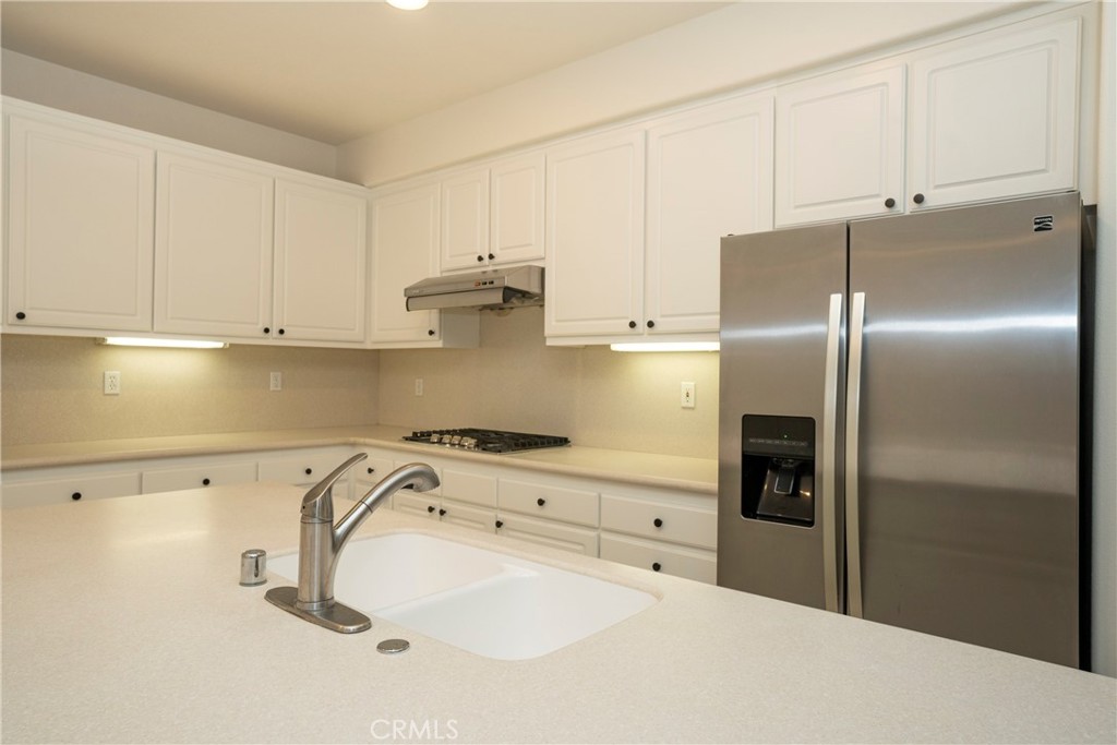6319 Lavender Street Eastvale, CA 92880 - Photo 12 of 39 a kitchen with a refrigerator and white cabinets